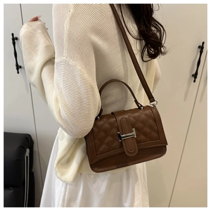 Détail d'un sac à main matelassé marron avec coutures élégantes et bandoulière