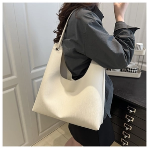 Détail de la texture cuir grainé blanc du sac cabas avec œillet sur la bandoulière