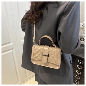 Quilted crossbody bag in beige leather with metal clasp shown on a model