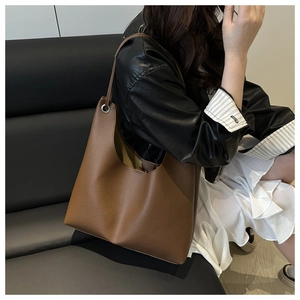 Détail du sac cabas marron foncé montrant la texture grainée et la bandoulière en cuir
