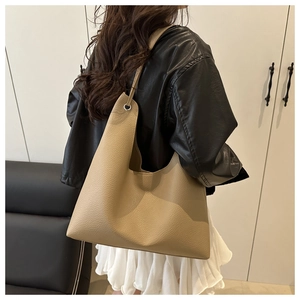 Detail of khaki pebbled leather texture on minimalist tote bag with metal eyelet