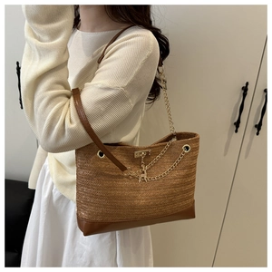 Detail of straw woven tote with brown leather base and deer charm for summer vacations