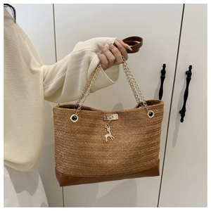 Détail du sac cabas en paille tressée avec chaîne dorée et pendentif cerf