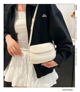 White minimalist saddle bag shown on a model with a focus on its smooth matte leather texture