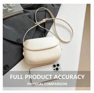 Detail of cream saddle crossbody bag showing matte texture next to a smartphone