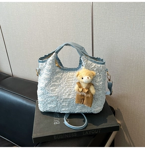 Detail of blue textured bubble fabric tote bag featuring a cute yellow plush bear charm