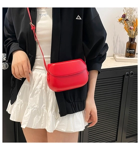 Chic red saddle bag in matte leather featuring a flap closure and adjustable strap