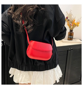 Rear view of a model wearing a minimalist red leather saddle bag with flap design