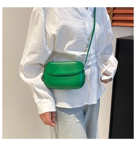Close-up of bright green semi-circular crossbody bag featuring sleek PU leather and flap design