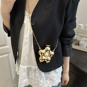 Elegant gold flower acrylic clutch with pearl center and metal chain over black blazer