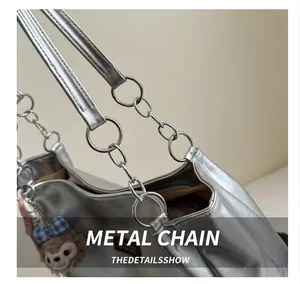 Detail of silver metallic tote bag showing metal ring link and plush doll pendant