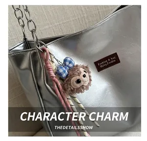 Close-up of silver cracked leather tote bag with a brown plush animal charm and chain