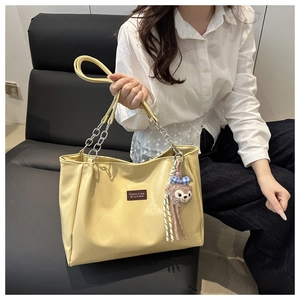 Close-up of cream leather tote bag with silver chain strap and cute bear charm