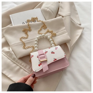 Detail of pink and white cherry print handbag with pearl handle and golden chain strap