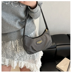 Dettaglio della texture della borsa a mezzaluna grigia e placca logo in metallo moda