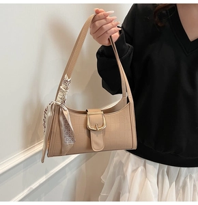 Détail du sac beige à motif crocodile avec boucle dorée et foulard en soie décoratif