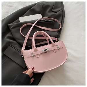Dettaglio della borsa a sella rosa con chiusura a scatto su blazer grigio scuro