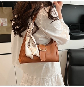 Dettaglio borsa a spalla marrone vintage con stampa coccodrillo, fibbia d'oro e foulard