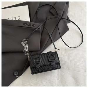Close-up of black mini crossbody bag with carbon fiber texture and acrylic chain
