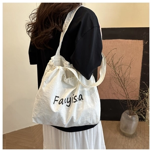 Détail d'un grand sac cabas blanc en toile avec cordon de serrage et imprimé artistique