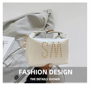 Détail d'un sac à bandoulière en cuir PU blanc avec motif de lettres SM en rivets dorés
