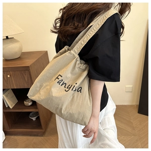 Détail du sac fourre-tout en toile beige avec cordon et lettrage noir Fanyisa