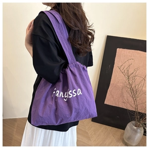 Detail of a large purple tote bag with white lettering and crinkled nylon texture