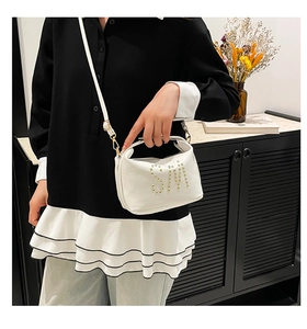 Détail du sac cabas blanc brillant avec logo SM en perles porté par un mannequin de mode