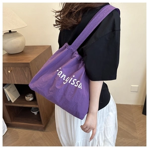 Détail du sac fourre-tout violet à cordon avec lettrage fanyissa blanc sur tissu doux