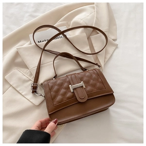 Vue détaillée du sac matelassé marron avec boucle H argentée sur un blazer chic
