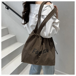 Détail d'un grand sac cabas marron foncé avec cordon de serrage et logo Farissa
