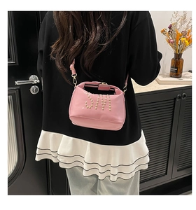 Sac fourre-tout rose avec logo SM clouté doré porté par un mannequin dans un salon