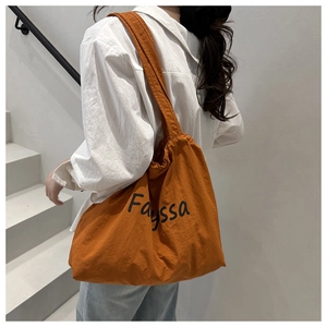 Rückansicht eines Modells mit einer karamellorangen Stofftasche mit Fayssa Aufdruck