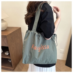 Olive green fabric tote bag detail with orange lettering and drawstring closure