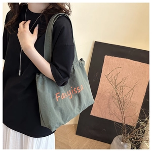 Detail of army green canvas tote bag with orange lettering and drawstring closure