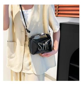 Détail du sac cabas en cuir verni noir avec lettres en perles et boucles dorées