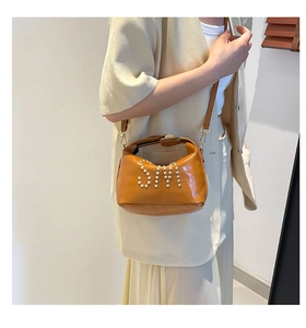 Détail du sac cabas en cuir marron vintage avec logo SN en rivets nacrés sur un mannequin