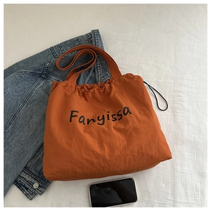 Detailansicht einer karamellfarbenen Nylon-Kordelzugtasche mit schwarzer Aufschrift