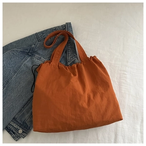 Draufsicht auf eine orangefarbene Kordelzug-Tasche kombiniert mit einer blauen Denim-Jacke