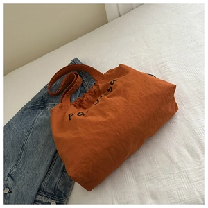 Detail der orangefarbenen Nylon-Einkaufstasche mit Kordelzug und strukturierter Optik