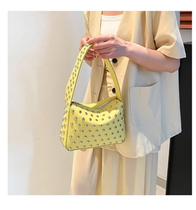 Macro shot of bright yellow studded shoulder bag with silver rivets and litchi texture