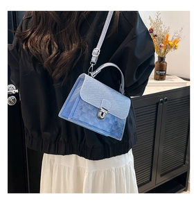 Gros plan d'un sac à main bleu clair en PVC avec texture et fermoir rotatif argenté