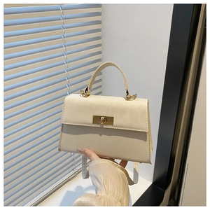 Detail of a beige trapezoid mini bag featuring a gold metal twist lock and top handle