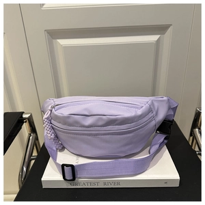 Detail of light purple nylon dumpling bag with adjustable strap and beaded pendant charm