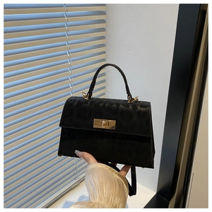 Detail of leopard print black crossbody bag with gold twist lock and sturdy handle