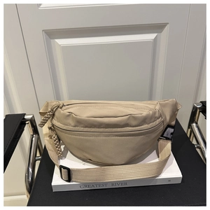 Detail view of khaki nylon waist bag featuring zip pockets and woven cord zipper pullers