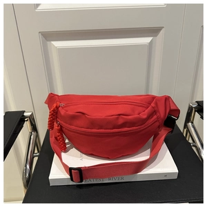 Detail of red nylon waist bag featuring dual zippers and adjustable buckle strap