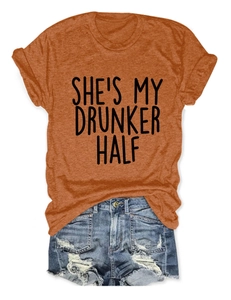 Close-up of orange cotton T-shirt with black She's My Drunker Half text and denim shorts