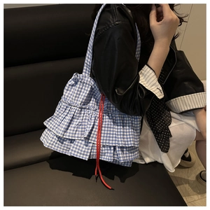 Détail du sac cabas à carreaux bleus avec volants étagés et cordon rouge décoratif