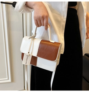 Detail view of contrast color handbag with top handle and adjustable shoulder strap